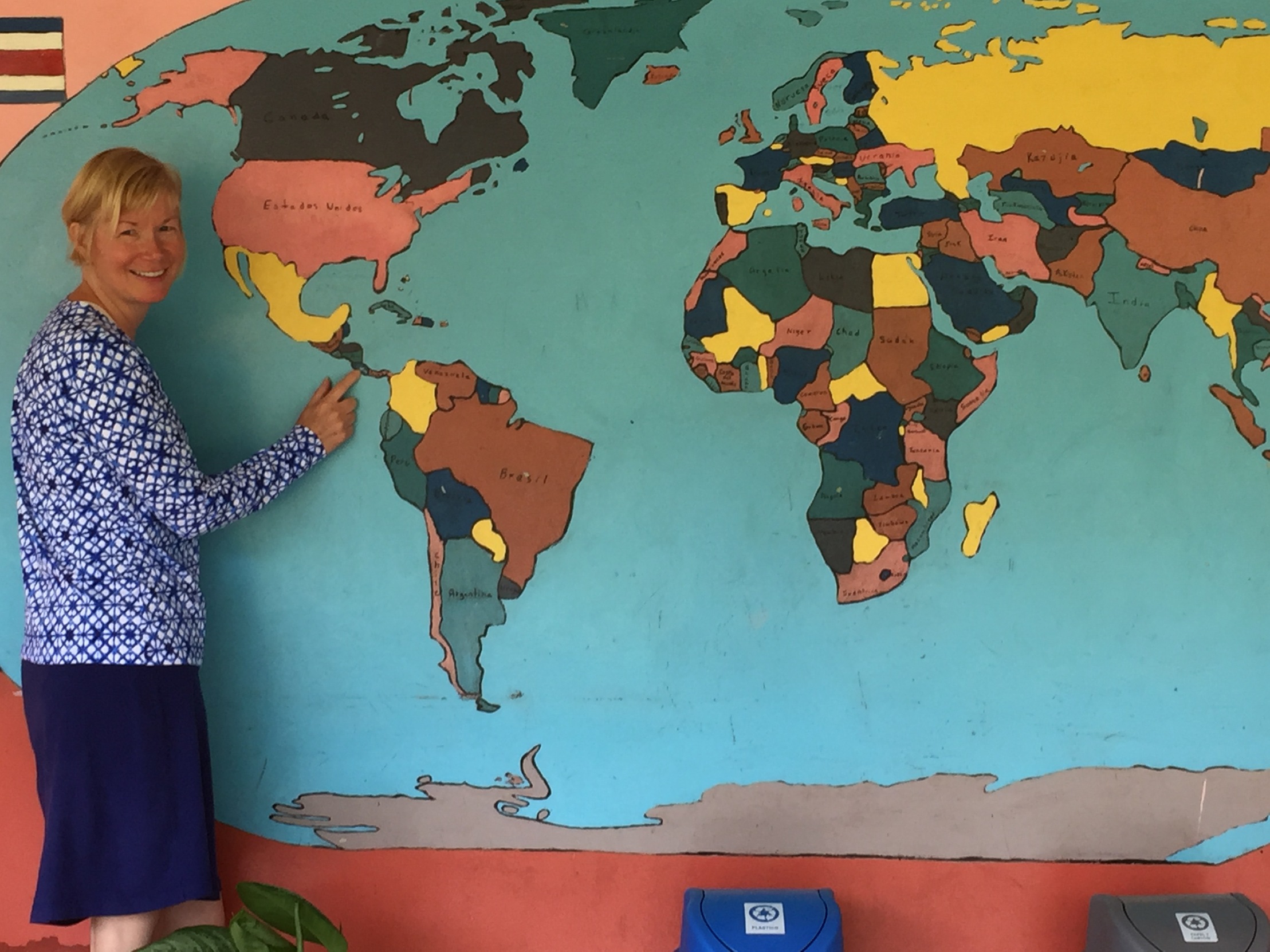 Smith in her Peace Corps village in 2018. The community came together to make a world map at the local school. Smith's former students have preserved the mural over the last 25+ years.